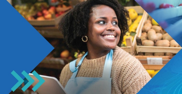 Employee in produce section of grocery store holding a smart tablet