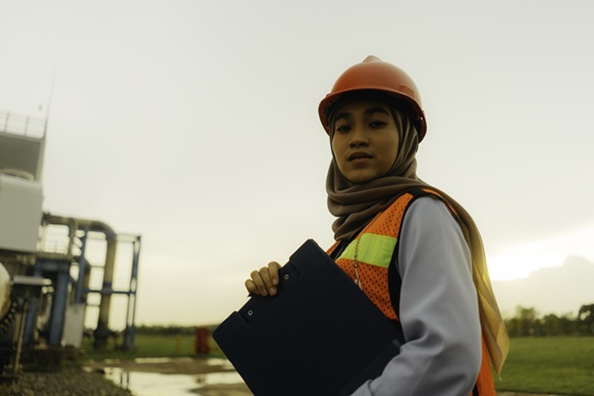 Une personne portant un gilet de sécurité aux Philippines et tenant un dossier sur un site de production d’énergie.